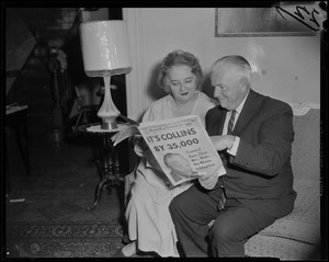 A man and woman on the couch reading from the Record American with headline "Council Race Close - Mrs. Hicks Big Winner in School Test"