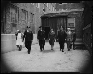 School Committee Chairman Louise Day Hicks, accompanied by a police guard, toured vandal-damaged Patrick Campbell School