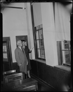 School Committee Chairman Louise Day Hicks with a man in a classroom with broken windows at Patrick Campbell School