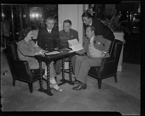 George Jessel and his wife Lois Andrews, seated, with 3 other men around them, including Lt. Commander Tom Collins and Lt. Joseph McDonough