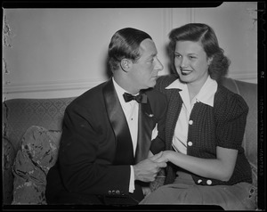 George Jessel and wife, Lois Andrews, seated on the couch
