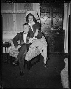 George Jessel and wife, Lois Andrews, seated on the chair