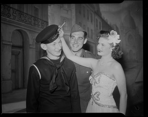 Lois Andrews signing a US Navy sailor's hat while another uniformed man looks on