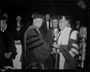 General Eisenhower in a robe and cap, shaking hands with Boston University President Daniel L. Marsh