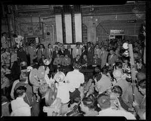 President Dwight Eisenhower seated at a table with other men, at what appears to be a press conference