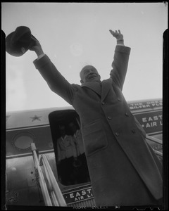 General Eisenhower with arms lifted above his head, waving from airplane steps