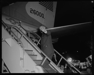 President Johnson waving while walking up the stairs to board a flight