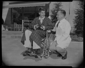 Prince Alexandre in a wheelchair with a doctor kneeling beside him