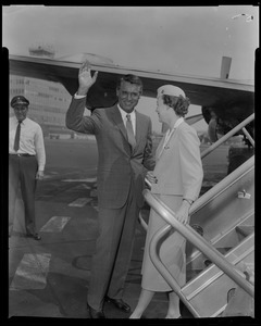 Cary Grant stands with stewardess Barbara Shephard and waves to the crowd