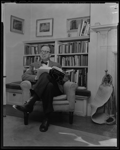 Arthur Schlesinger, Jr. seated in chair, with book