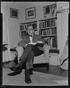 Arthur Schlesinger, Jr. seated in chair, with book