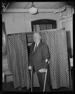 Mayor John F. Collins poses for the camera in front of voting booth