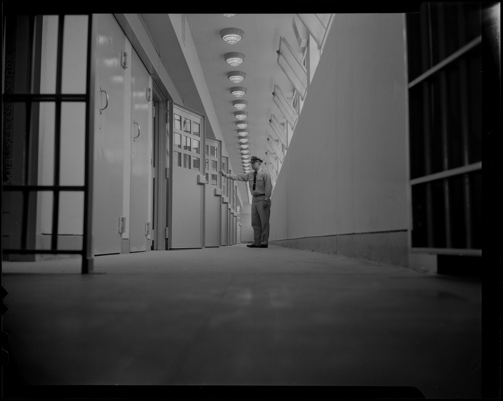 Prison guard standing at a row of cells