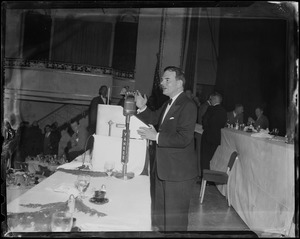 Governor Dewey at a podium with people standing in the background