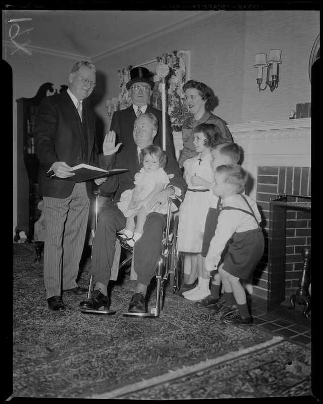 John F. Collins, a polio victim, is sworn in by Mayor John B. Hynes with his family around including wife Mary Patricia