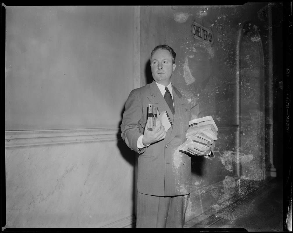 Senator John F. Collins with books in his arms during the State House Anti-Filthy Book Bill Hearing