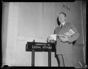 Senator John F. Collins with books in his arms during the State House Anti-Filthy Book Bill Hearing
