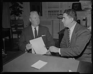 Mayor Collins holding a document while a man points something out