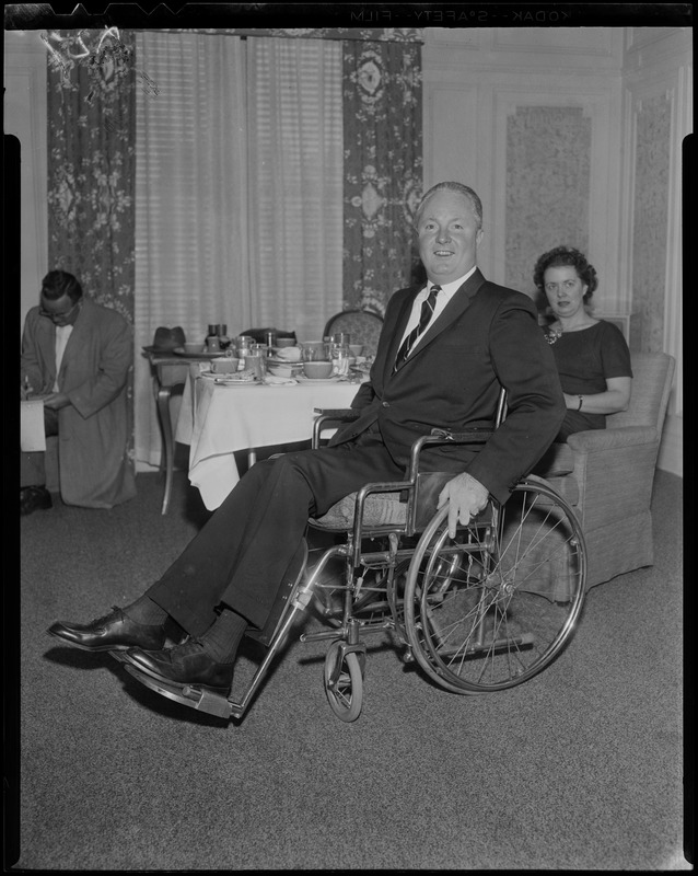 John F. Collins near the table with his wife Mary in the background