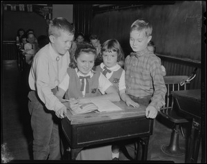 Mayor-elect John F. Collins's children, Thomas, Patricia, John, Jr., and Peggy at a desk in a school classroom