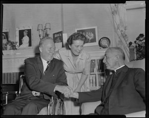 Mayor-elect John F. Collins shaking hands with a clergyman as wife Mary looks on