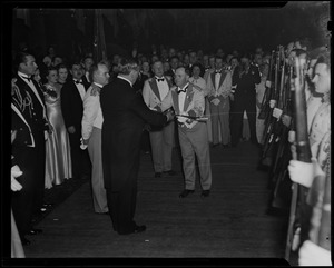Man presenting a sword to Governor James M. Curley, in front of the guard