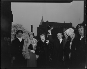Governor James M. Curley raising his hat while standing with son George Curley, daughter, Mary Curley, wife Gertrude, and others at the Inaugural Ball