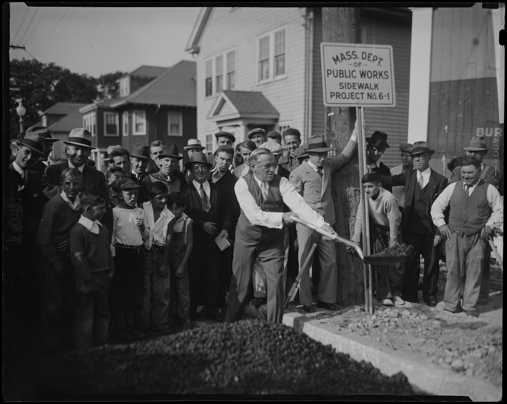 James M. Curley shovels with a group looking on during the Mass Dept of Public Works Sidewalk Project