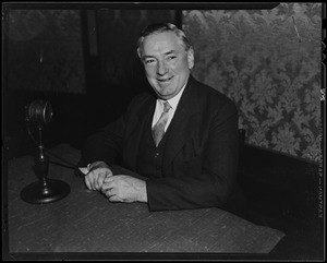 James M. Curley seated with microphone