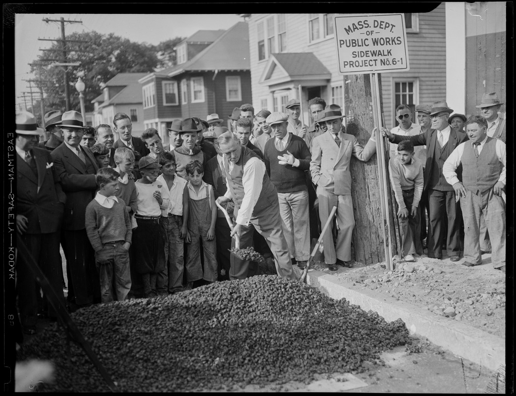 James M. Curley shovels with a group looking on during the Mass Dept of Public Works Sidewalk Project