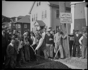 James M. Curley shovels with a group looking on during the Mass Dept of Public Works Sidewalk Project