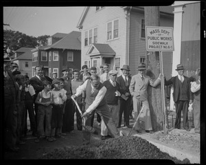 James M. Curley shovels with a group looking on during the Mass Dept of Public Works Sidewalk Project