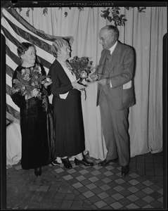 Two older woman holding flowers with an older man