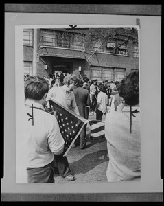 Photograph of a group of students with American flag striking in front of the Massachusetts National Guard headquarters