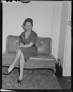 Lana Turner sitting on a chair, in Boston for press interviews for newest film "Imitation of Life"