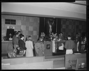 A view of people standing before an alter with two priests standing behind it