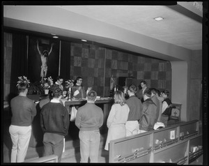 A view of people standing before an alter with two priests standing behind it