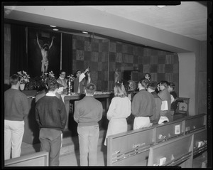 A view of people standing before an alter with two priests standing behind it