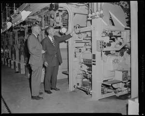 William Davis Taylor, publisher, showing a wheel on a machine to John I. Taylor, president