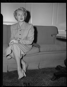 Lana Turner seated on a couch