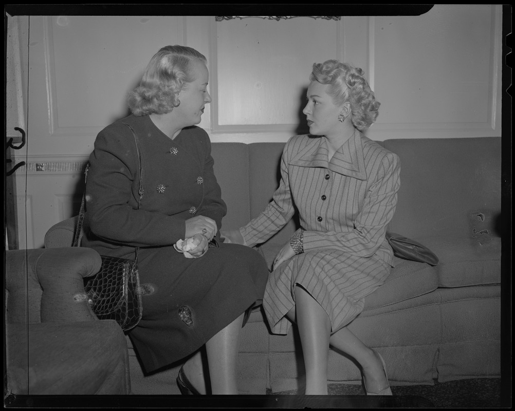 Lana Turner seated on a couch and talking with a woman