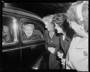 Lana Turner in the back of a car as woman look on