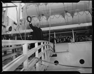 Cardinal Cushing waving his hat before joining the crowd on the ship