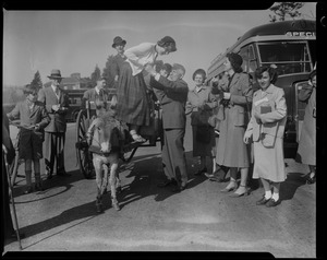 Man helping woman off of a wagon cart