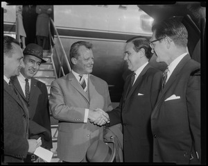 Willy Brandt, West Berlin mayor, shaking the hand of another man with two other men standing beside them