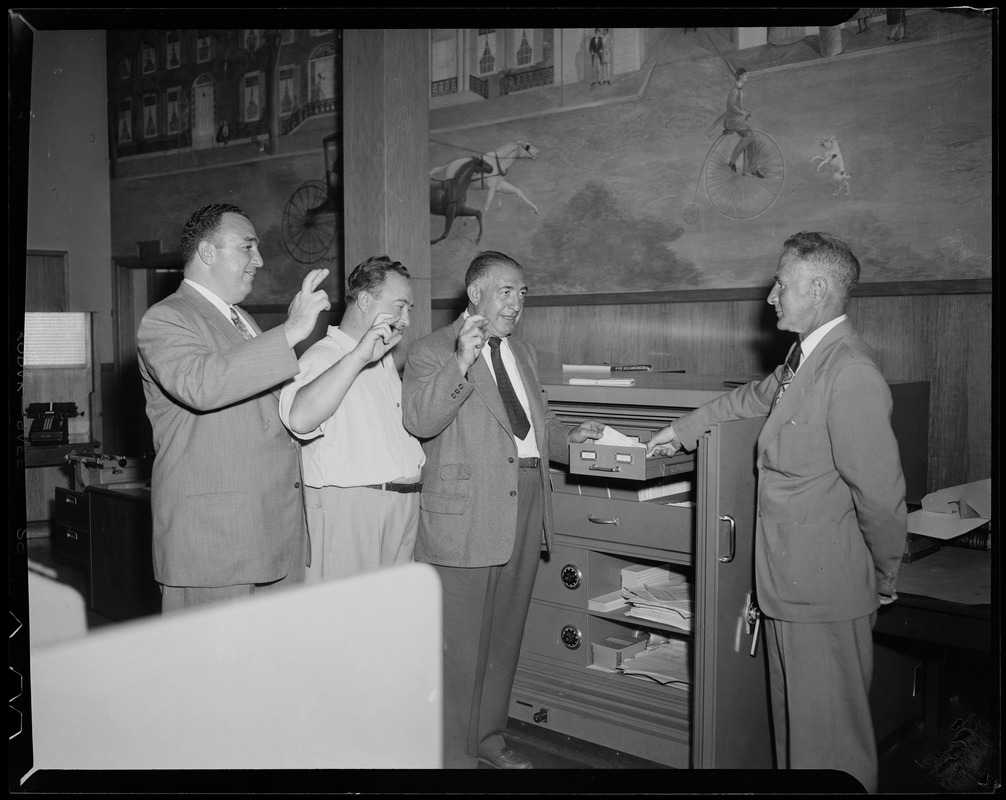 Three men crossing their fingers, including Sam Silverman, middle, in a Savings Life Insurance Bank as a deposit for $400,000 for the Marciano Wallcott fight happening in Boston is made