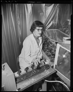 A woman at a machine, possibly made for negative film or lenses