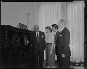 Harold G. Kern of Hearst Corp. with two young people and Rev. Dr. Harold C. Case, BU President, opening a door on a furniture piece