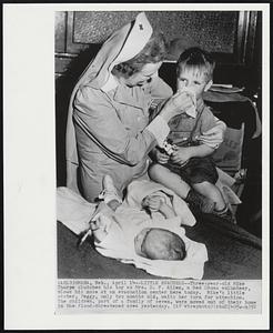 Little Evacuees -- Three-year-old Mike Thorpe clutches his toy as Mrs. D.F. Allen, a Red Cross volunteer, blows his nose at an evacuation center here today. Mike's little sister, Peggy, only two months old, waits her turn for attention. The children, part of a family of seven, were moved out of their home in the flood-threatened area yesterday.
