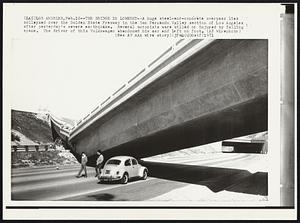 The Bridge is Lowered -- A hugh steel-and-concrete overpass lies collapsed over the Golden State Freeway in the Sa Fernando Valley section of Los Angeles after yesterday's severe earthquake. Several motorists were killed or injured by falling spans. The driver of this Volkswagen abandoned his ear and left of foot.